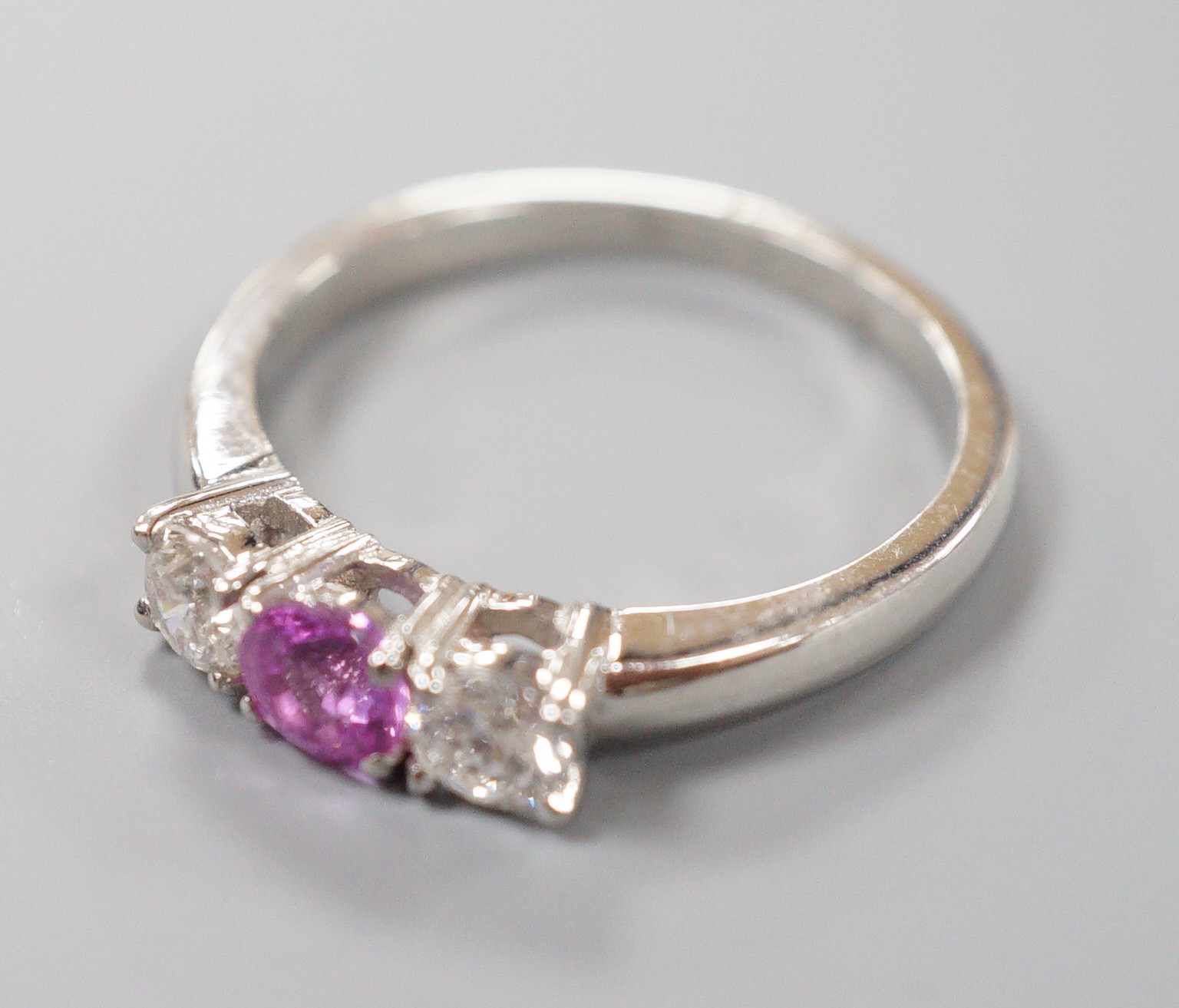 A modern platinum, pink sapphire and two stone round cut diamond set ring, size O, gross weight 5.4 grams